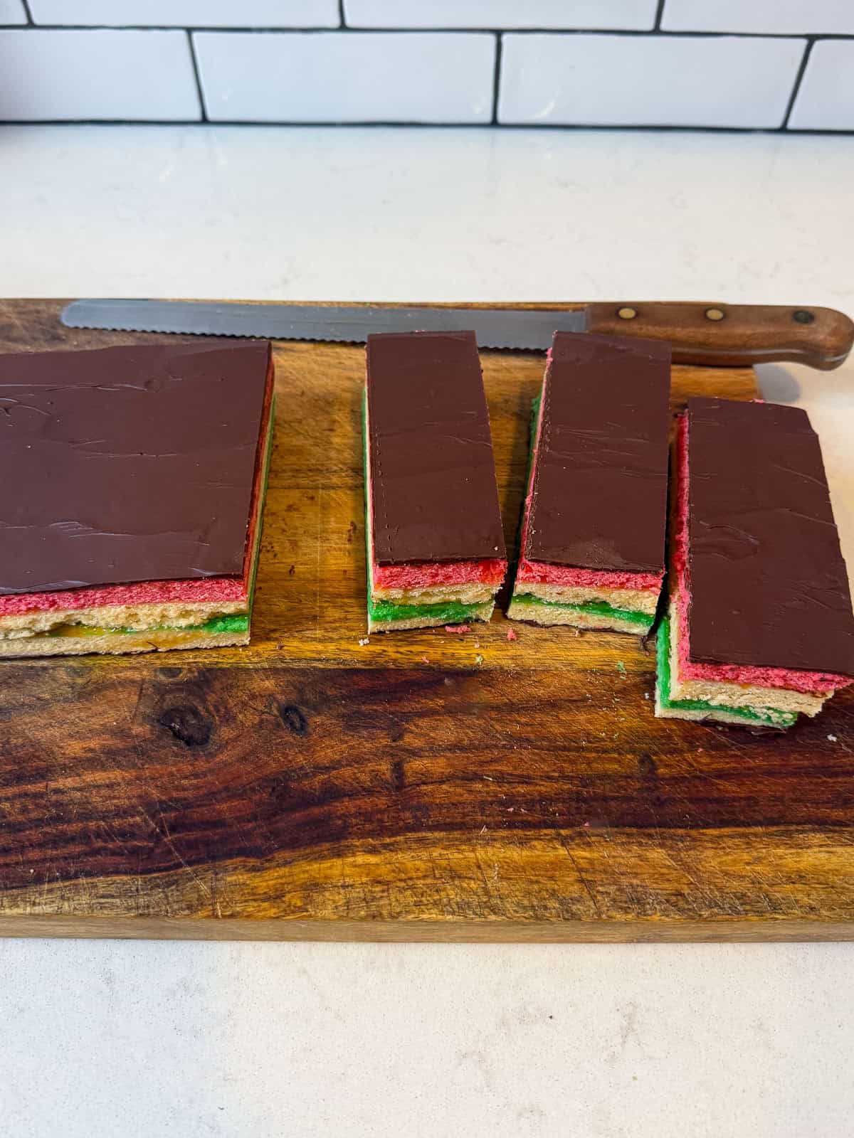 Use a clean serrated knife to cut the sheet of rainbow Italian cookies into long pieces and then into squares.