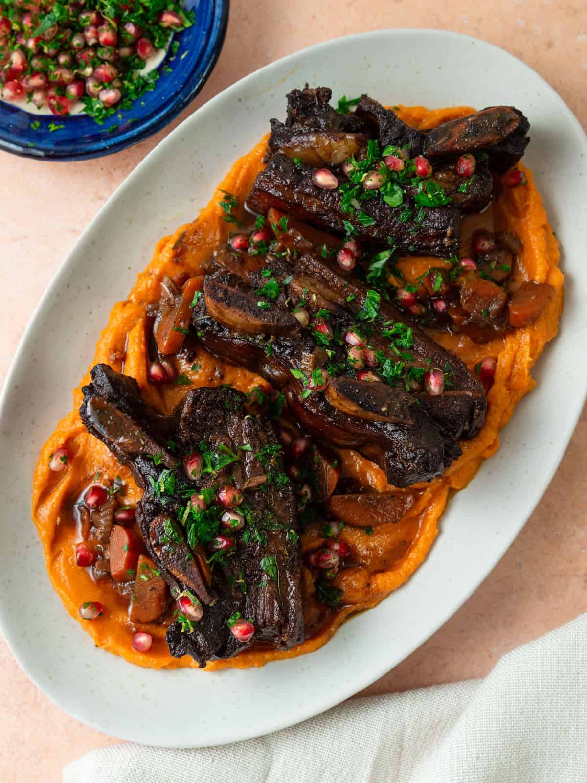 Tender pomegranate short ribs are4 served over creamy mashed sweet potatoes and garnished with a pomegranate gremolata.