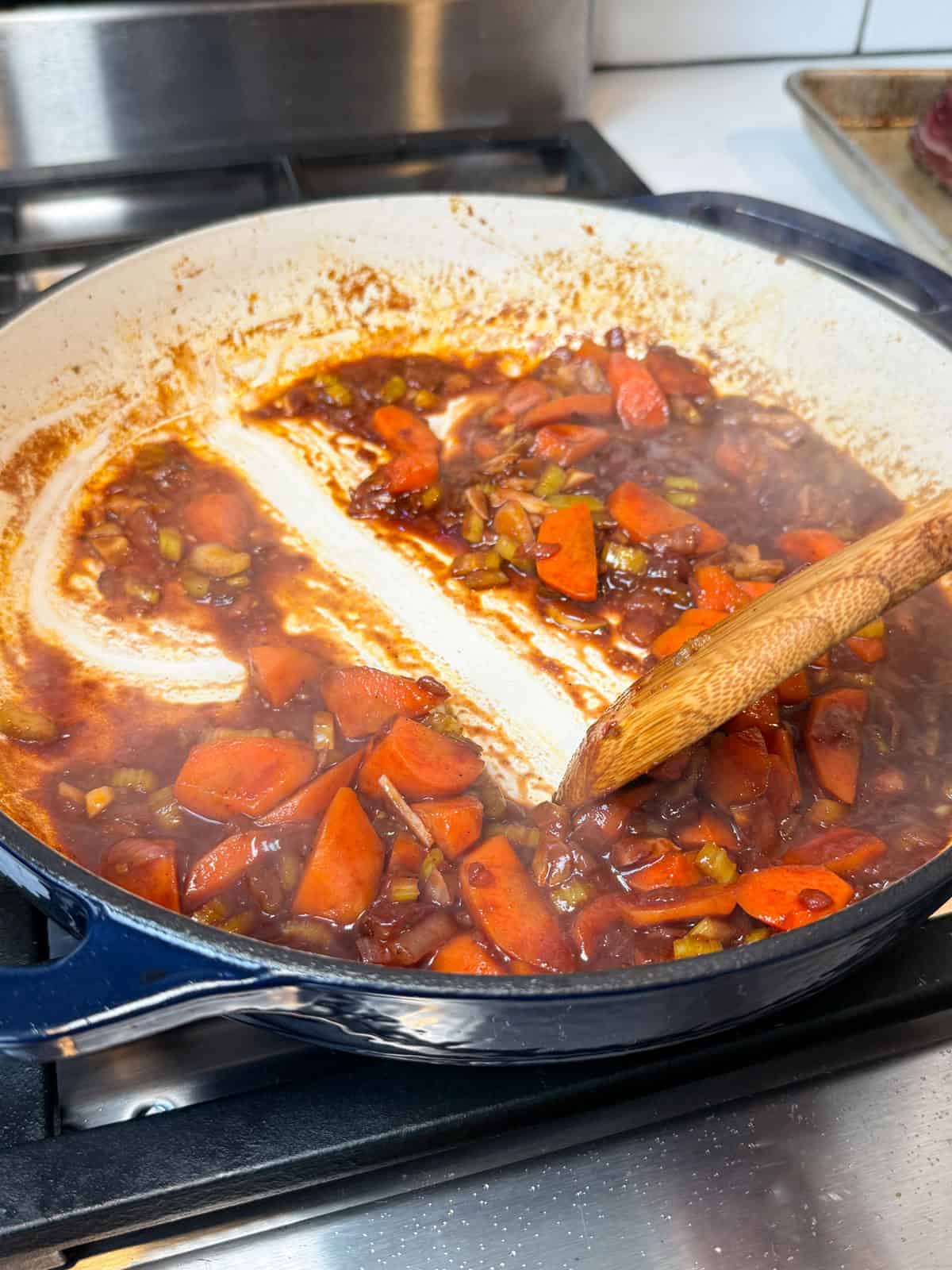 Add red wine to the sautéed vegetables and simmer to reduce the wine.