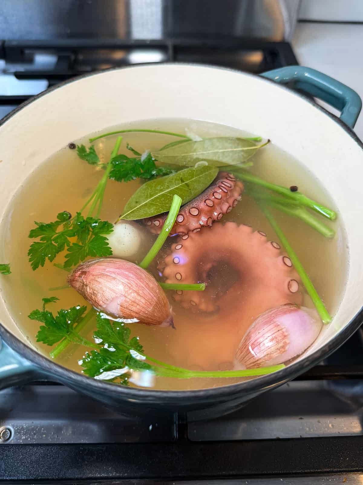 Simmer the octopus tentacles in the aromatic broth.
