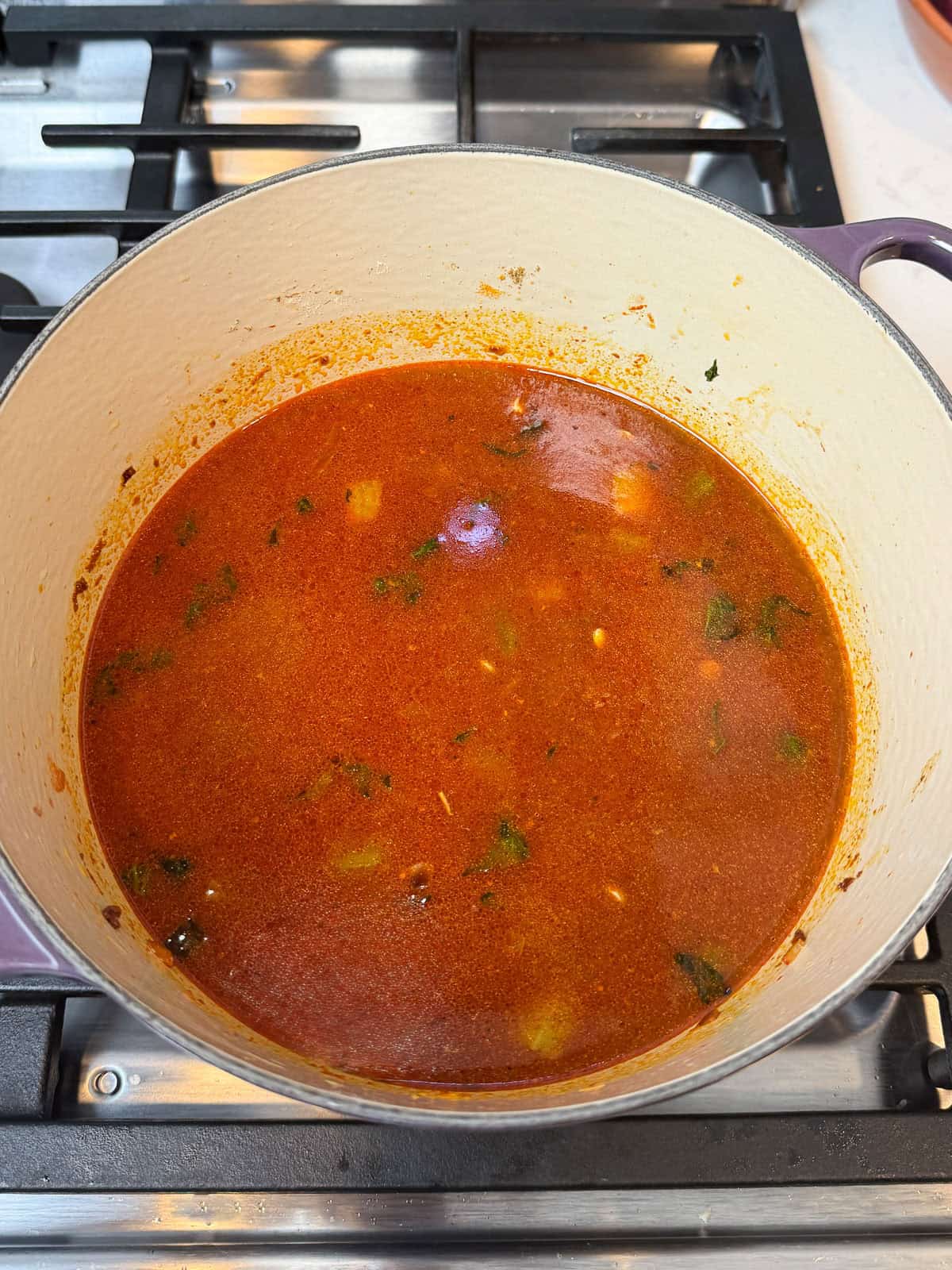 Add lentils and tomato sauce to the sautéed vegetables and start simmering the lentil soup.
