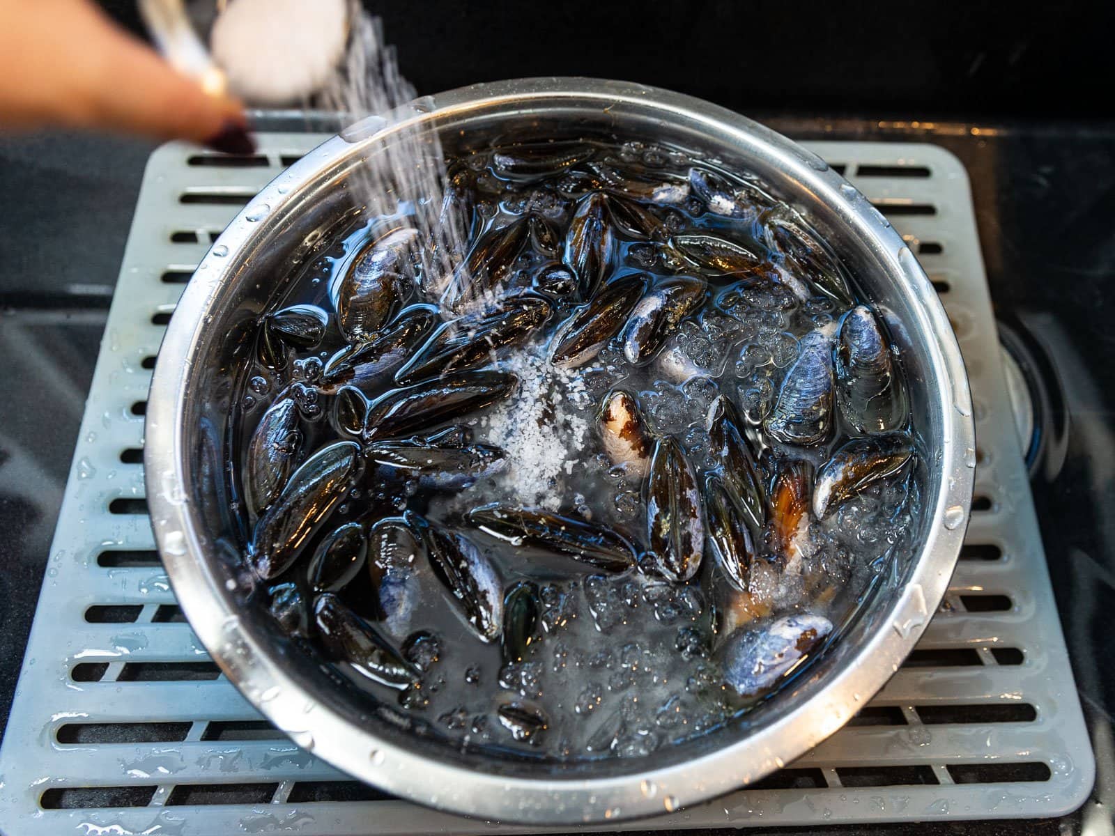 Once the fresh mussels are in a bowl of ice cold water, add a good amount of Kosher salt and let them soak for 30 minutes.