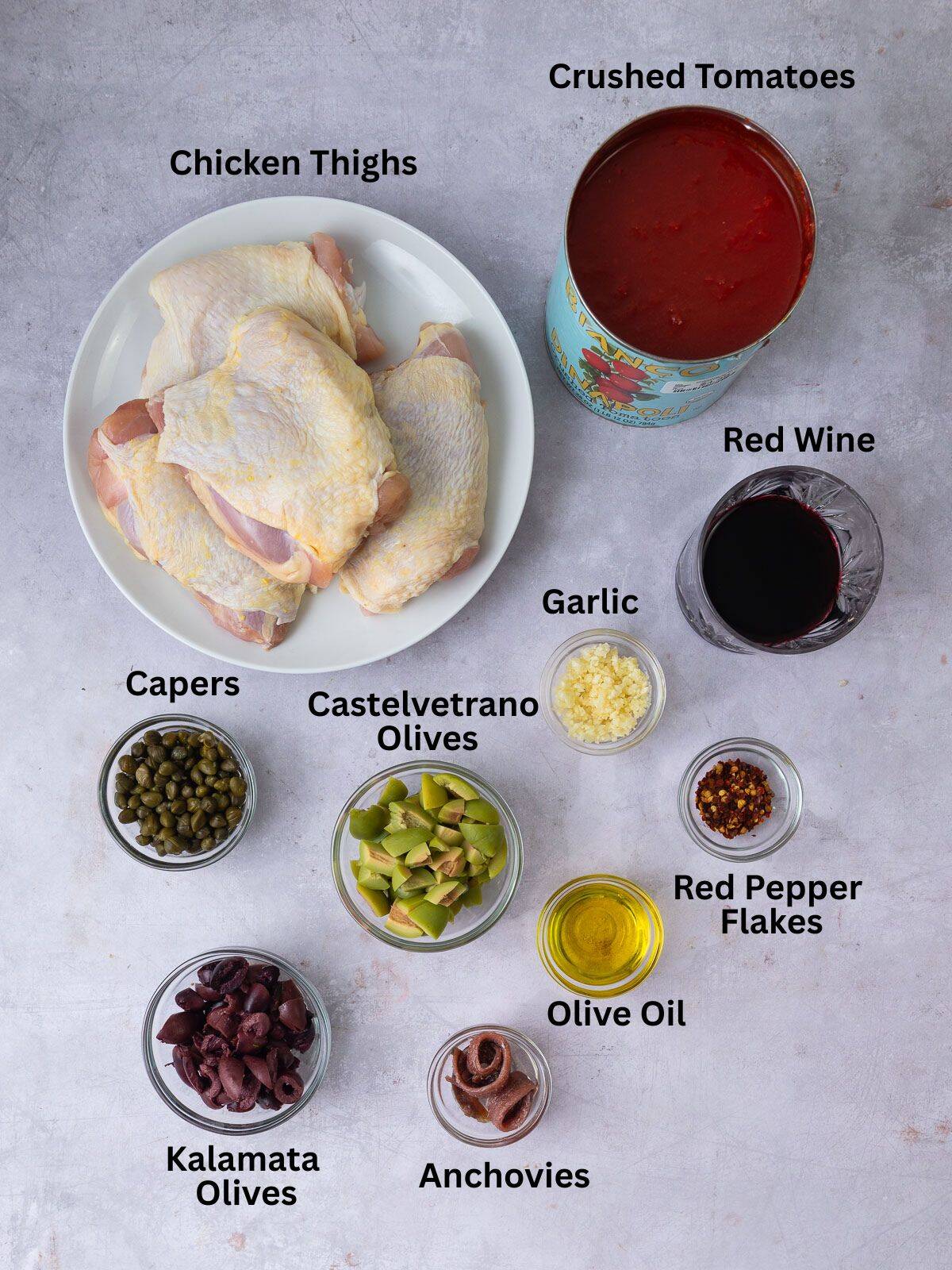Ingredients for chicken puttanesca, including anchovies, olives, capers and tomatoes.