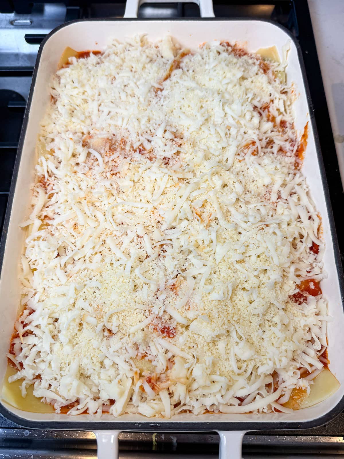 Once all the layers are done, scatter shredded mozzarella all over the top of the zucchini lasagna.