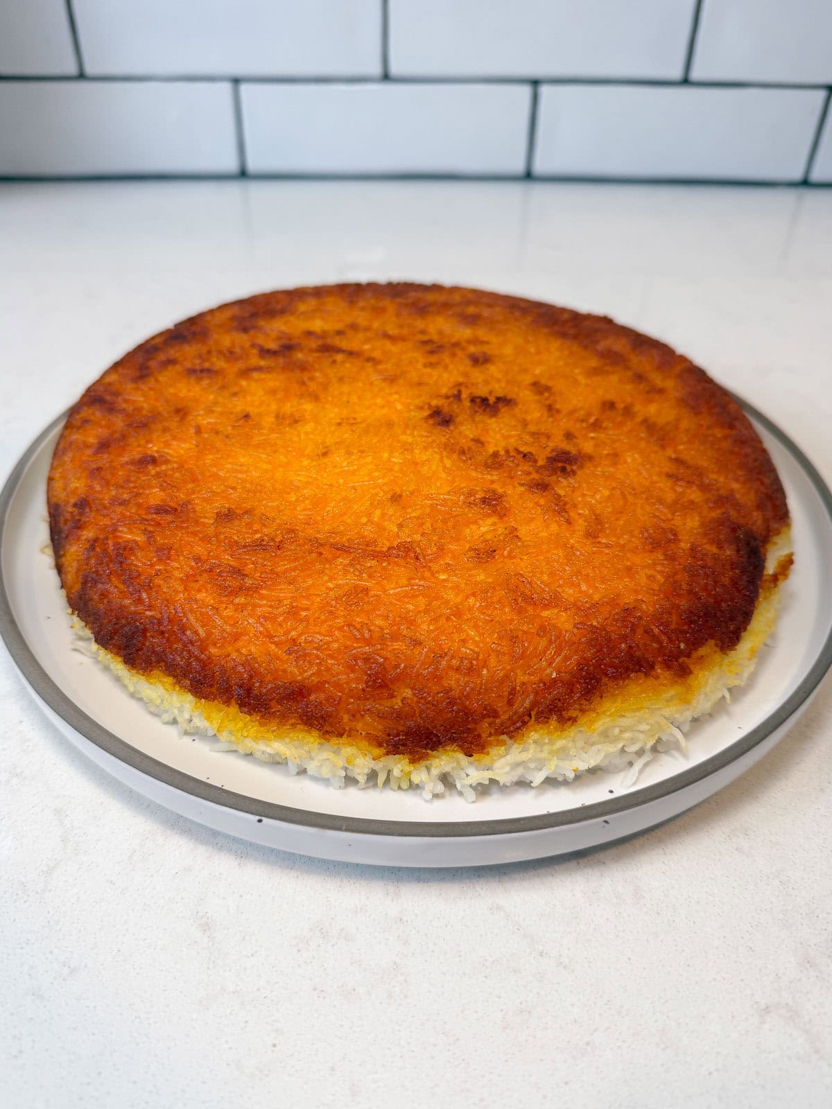 Once the rice is done, flip the tahdig onto a wide plate, it should release from the pan easily and be a even, golden and crispy.