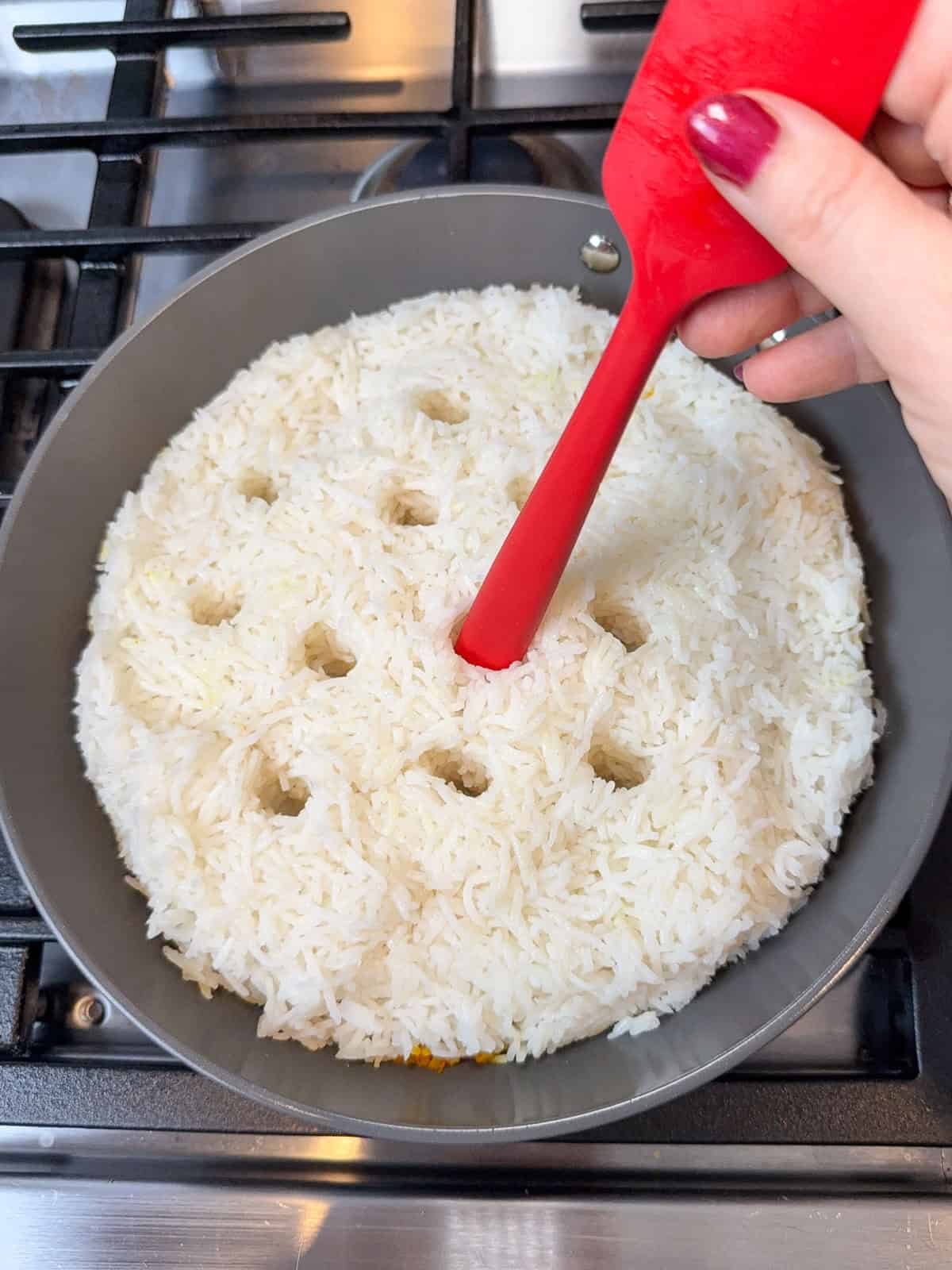 Add the rest of the par-cooked rice to the skillet and use the handle of the spatula to poke several holes into the rice, being careful not to poke all the way down to the bottom.
