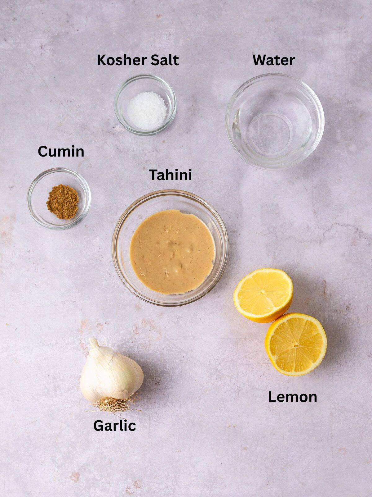 Ingredients for lemon tahini sauce with garlic and cumin.