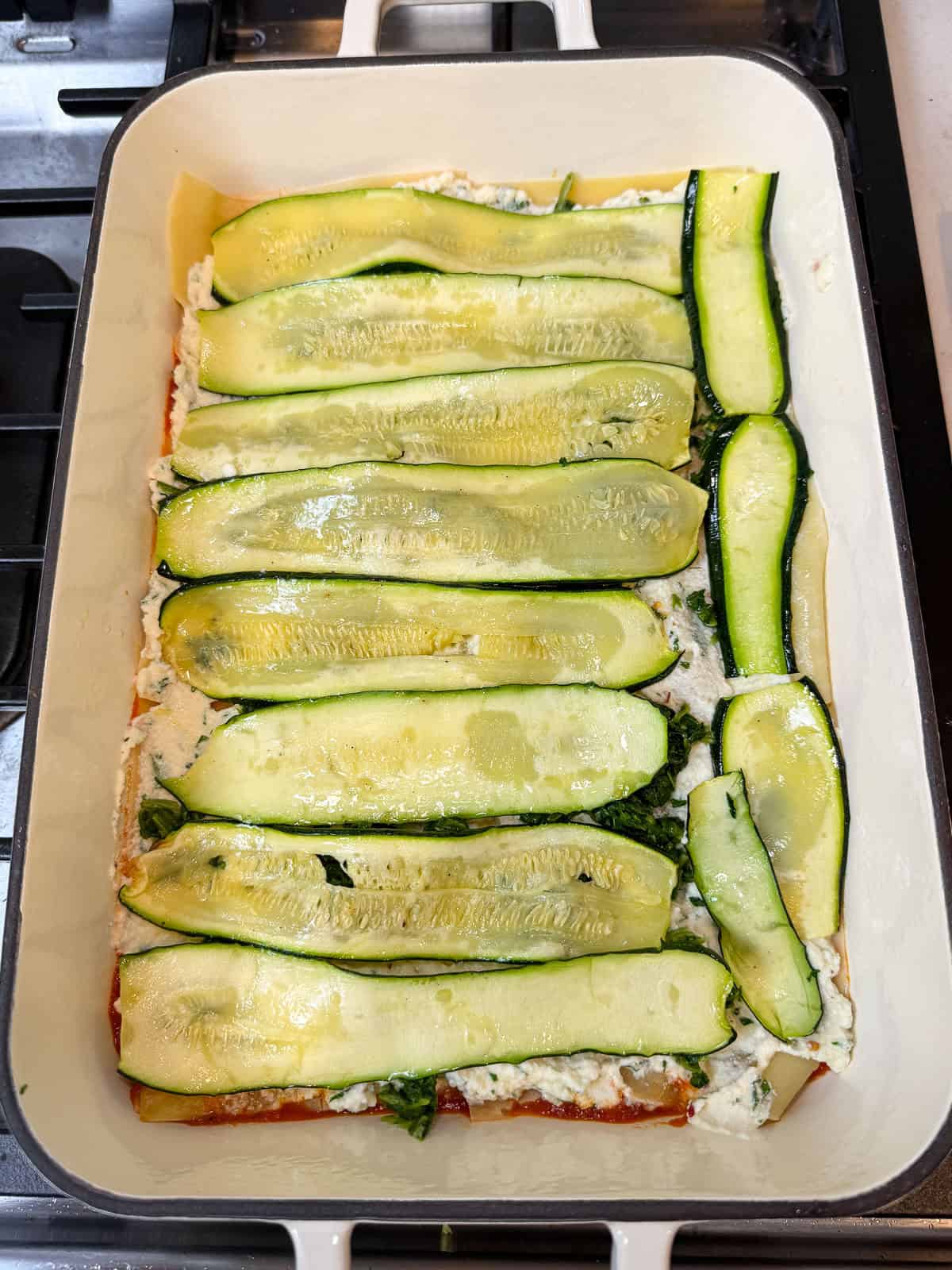 Layer the sliced zucchini on top of the spinach and ricotta layers.