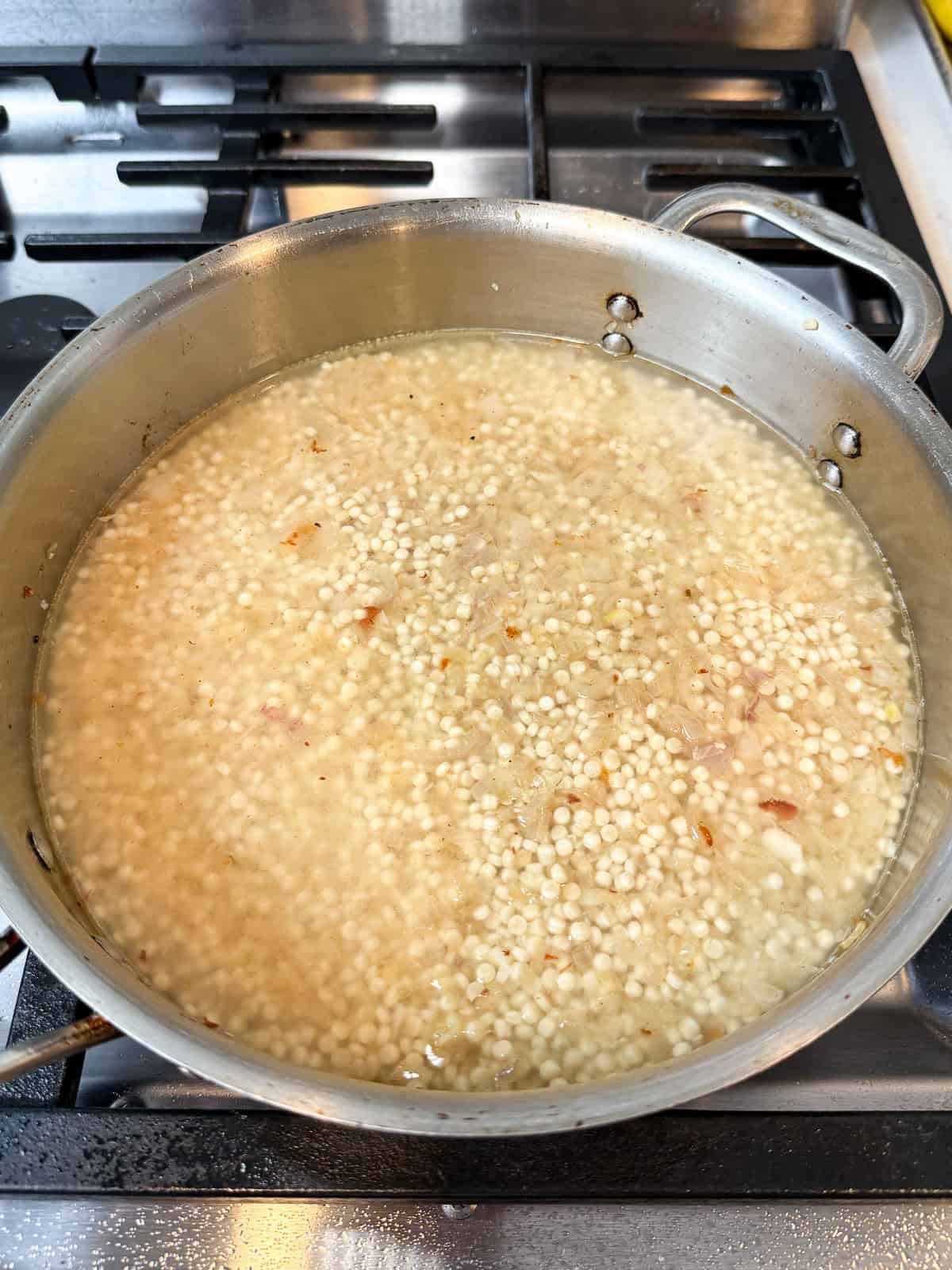 Add stock to the toasted pearl couscous and bring to a simmer.