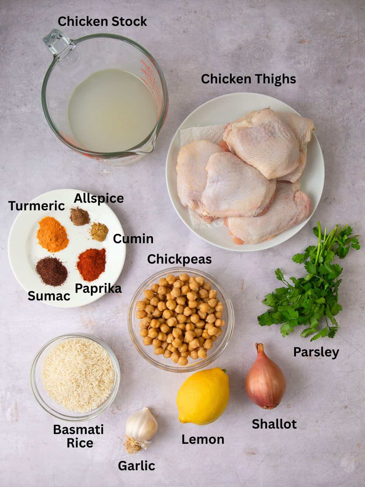 Ingredients for one pot chicken with rice and chickpeas, including Mediterranen spices, shallot, garlic and lemon.