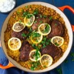 One pot chicken with rice and chickpeas is seasoned with bold spices and layered with fresh lemon slices.