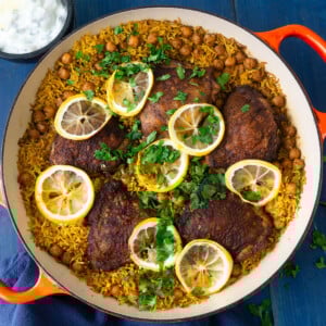 One pot chicken with rice and chickpeas is seasoned with bold spices and layered with fresh lemon slices.