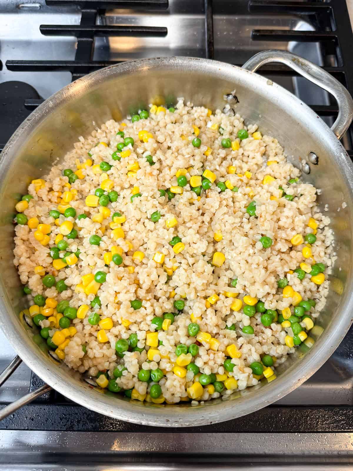 Once the pearl couscous is cooked and tender, add the corn and peas and toss to combine.
