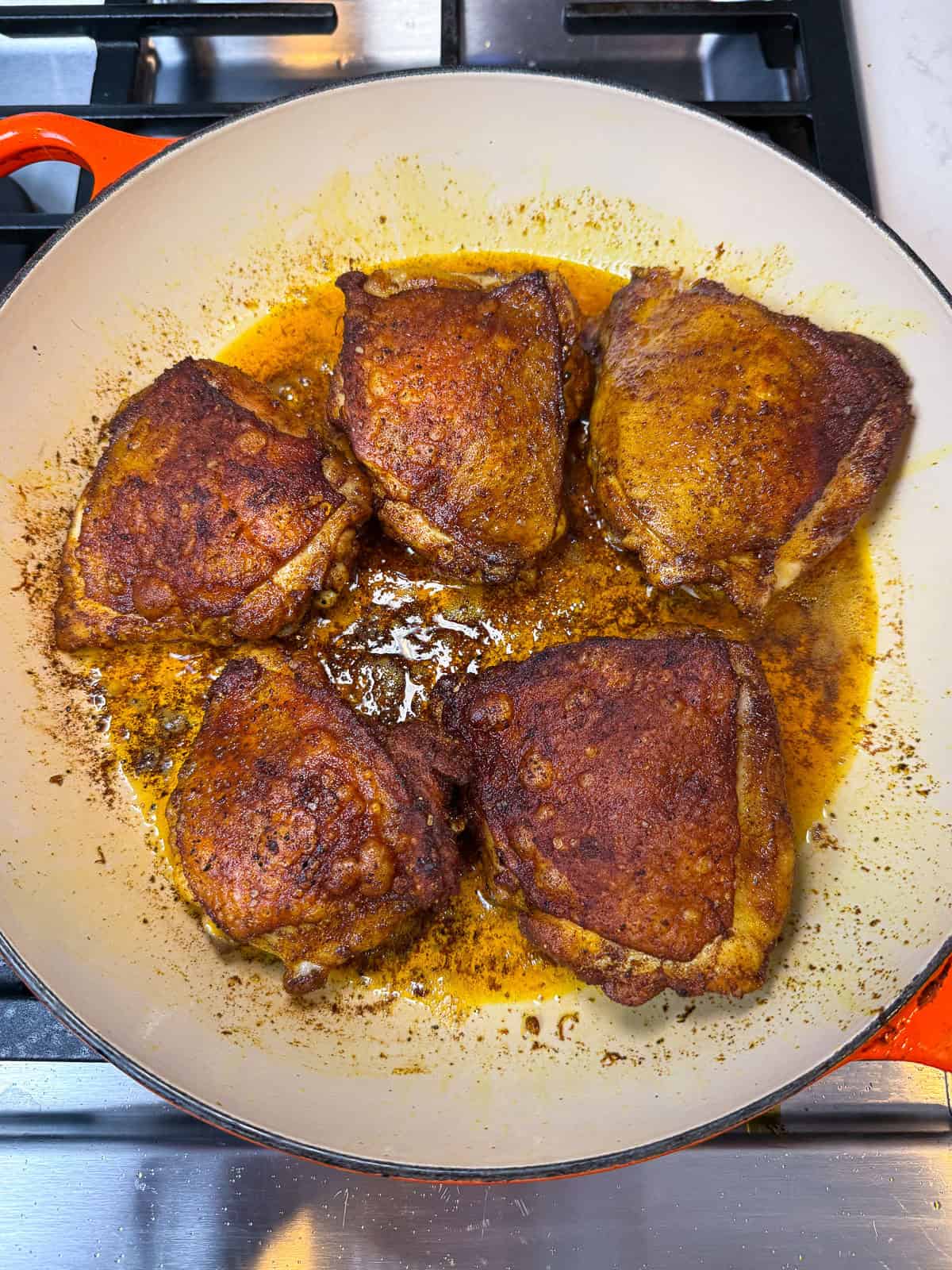 Sear the spiced chicken thighs on both sides until the skin is deeply seared.