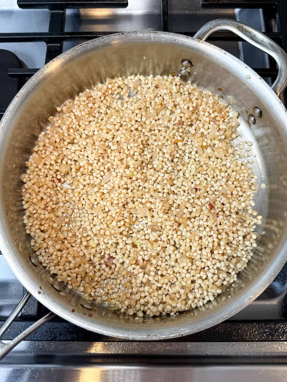 Toast the pearl couscous in the pan for a minute.