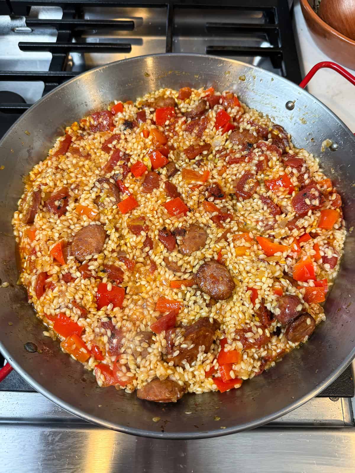 Add cooked chorizo to the paella rice and vegetables.
