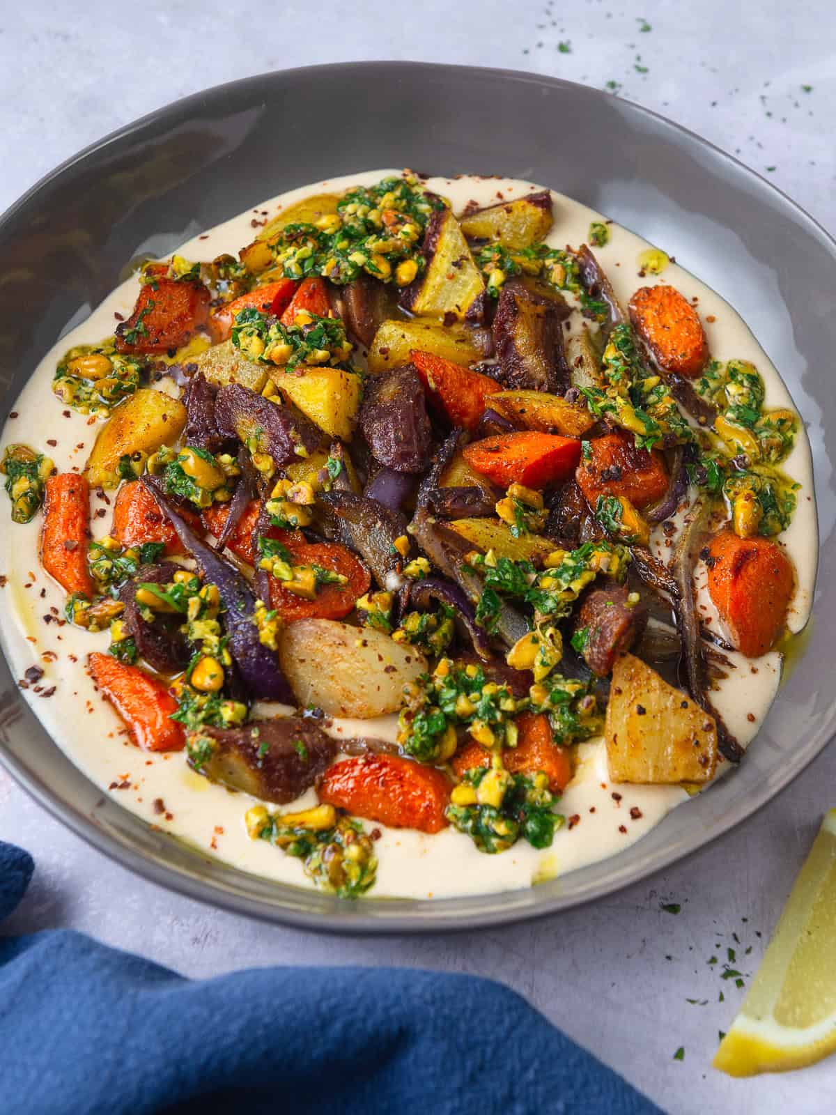Cumin roasted carrots and onions are served over creamy tahini sauce and finished with an herby pistachio gremolata.