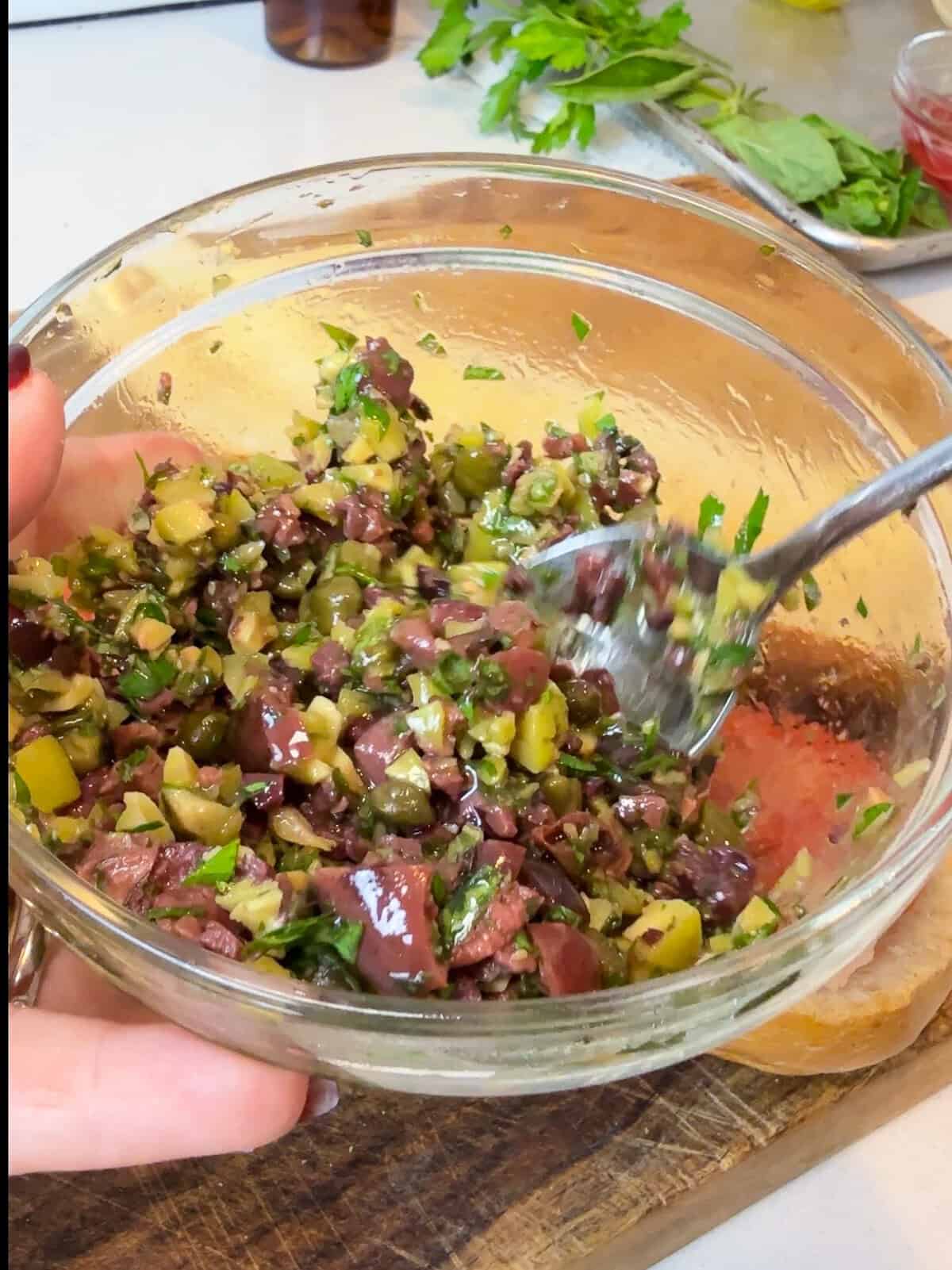 Toss the chopped olives with capers, herbs, olive and vinegar for the nicoise sandwich.