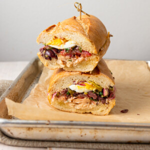 This nicoise sandwich is inspired by the French sandwich called pan bagnat and is layered with tuna, chopped olives, a perfect medium boiled egg and pickled onions.