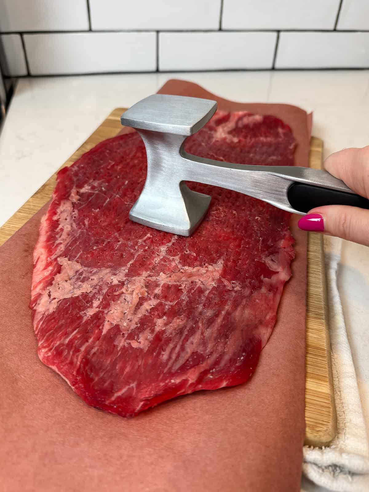 Use a meat mallet to flatten the flank steak into an even layer.