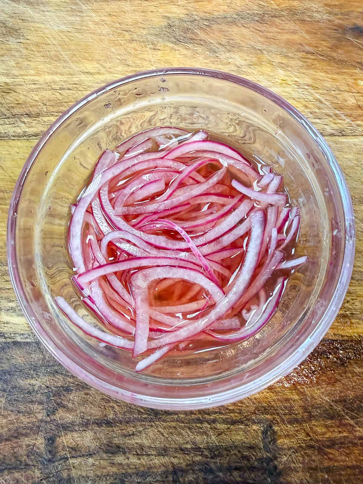 Add red wine vinegar to sliced red onions with a pinch of sugar to make quick pickled onions.
