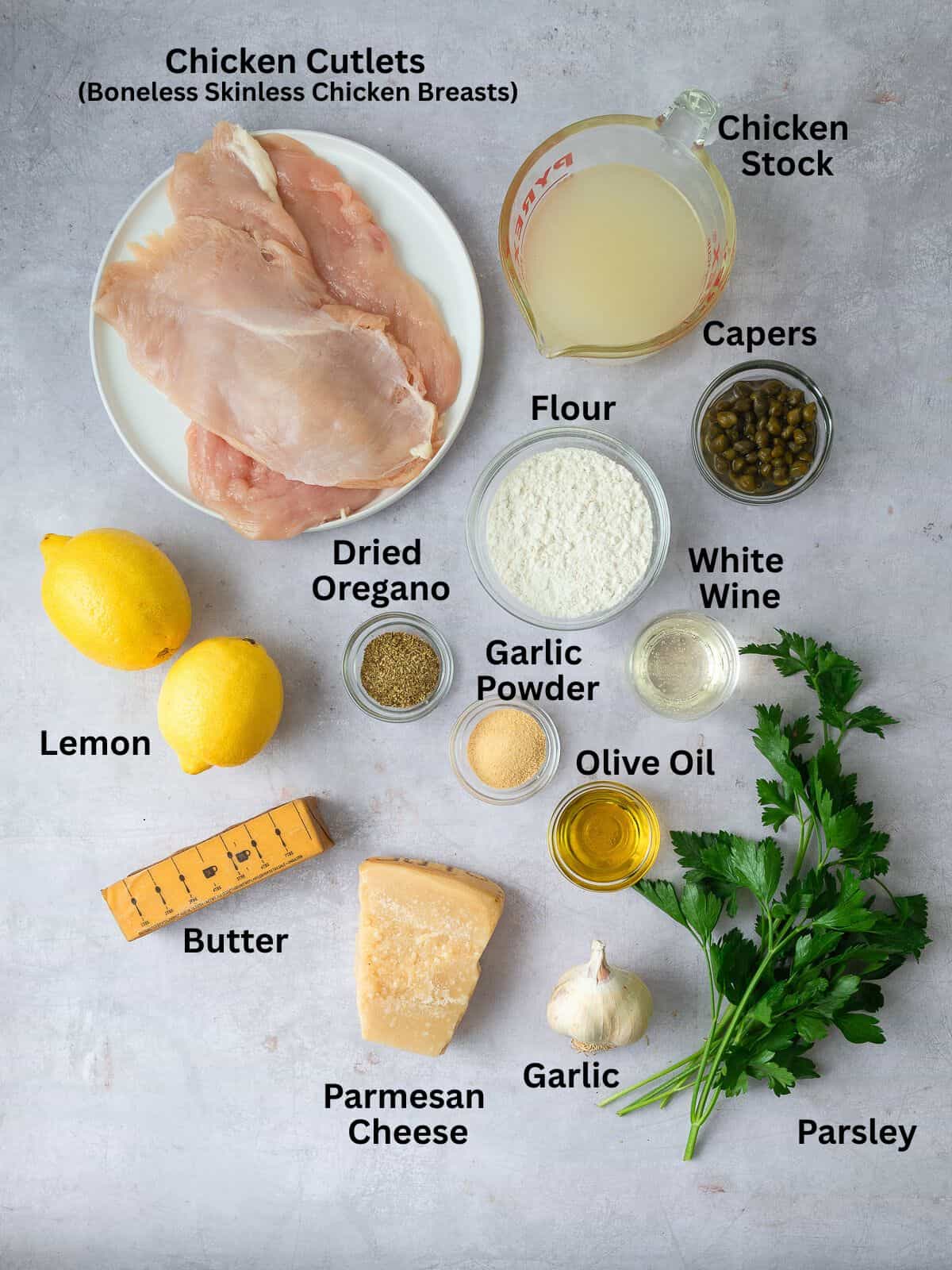 Ingredients for chicken piccata, with chicken cutlets, lemon, butter, capers and fresh herbs.
