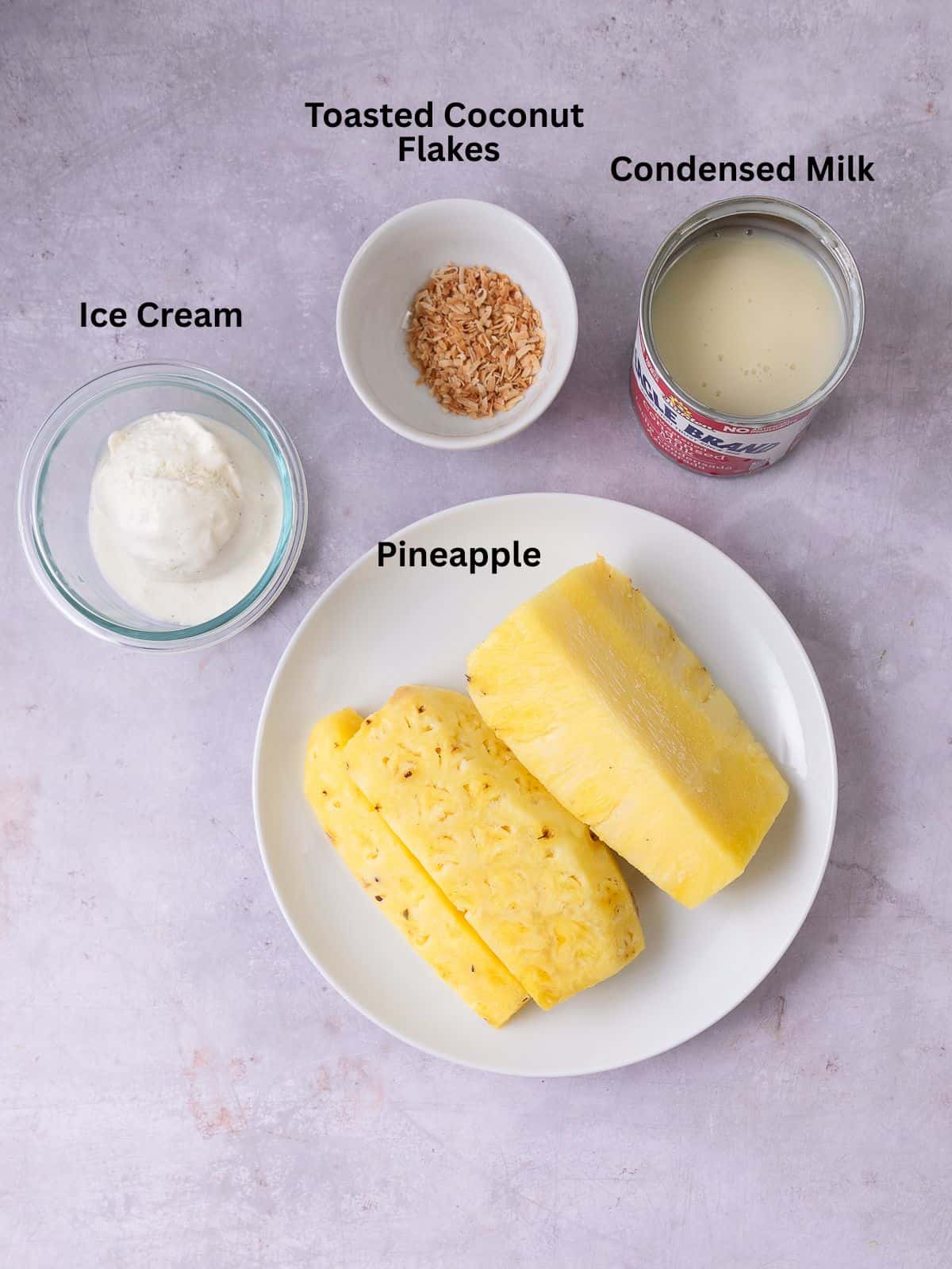 Frozen shaved pineapple dessert ingredients with ice cream, condensed milk and toasted coconut flakes.