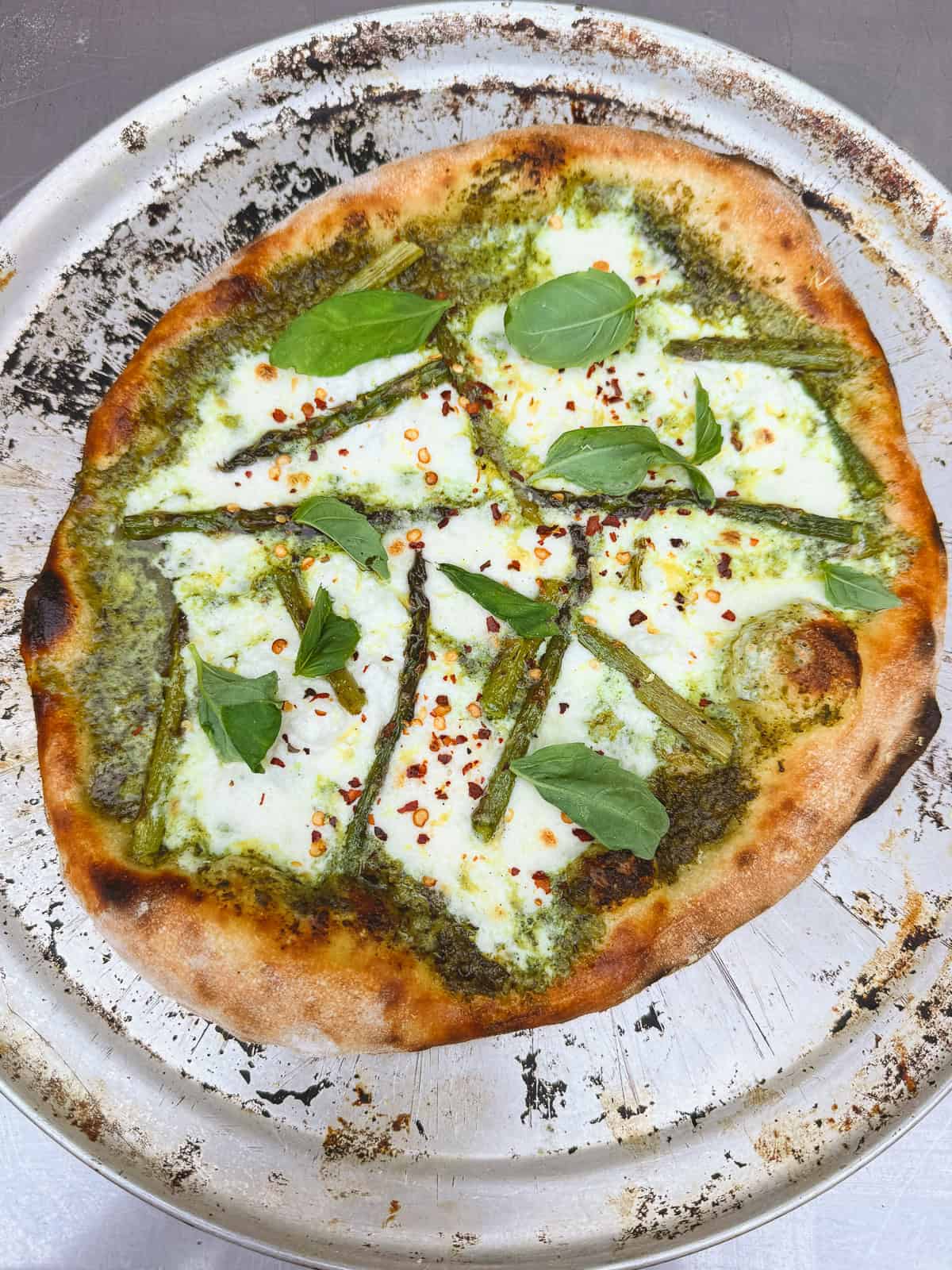 Garnish the pesto pizza with lemon zest and fresh basil.