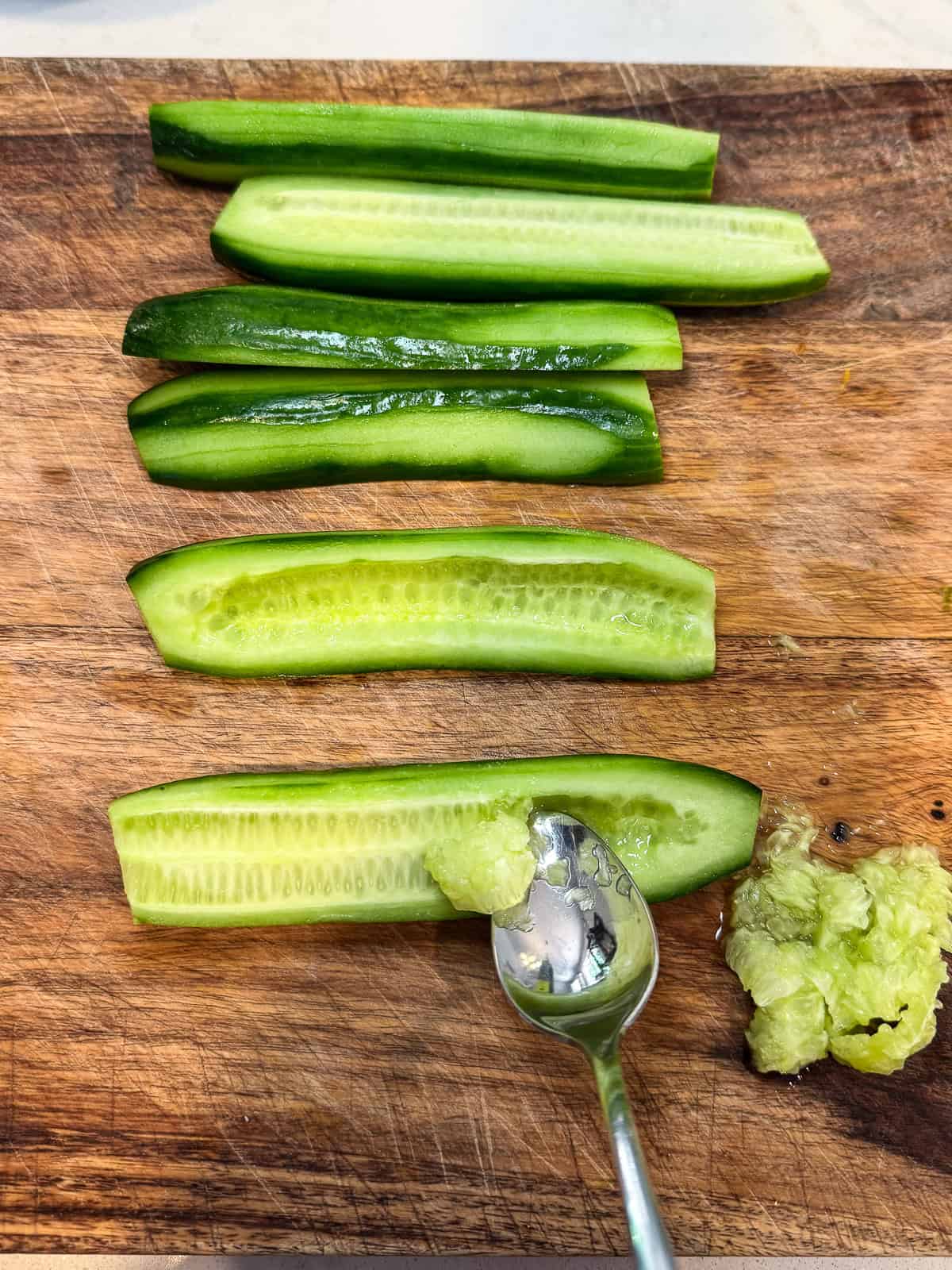 Use a spoon to scoop out the seeds from the center of the Persian cucumber.