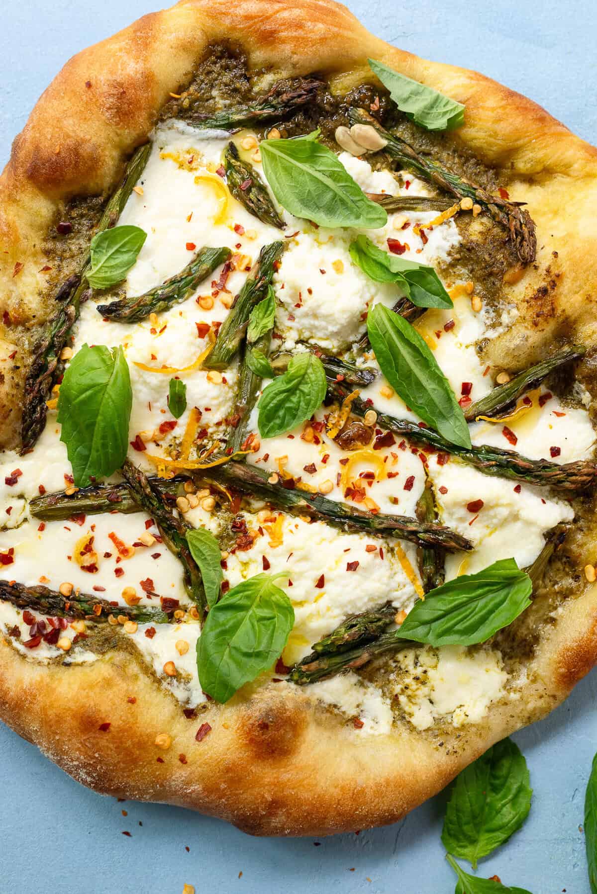 This white pizza is layered with pesto, asparagus and fresh basil.