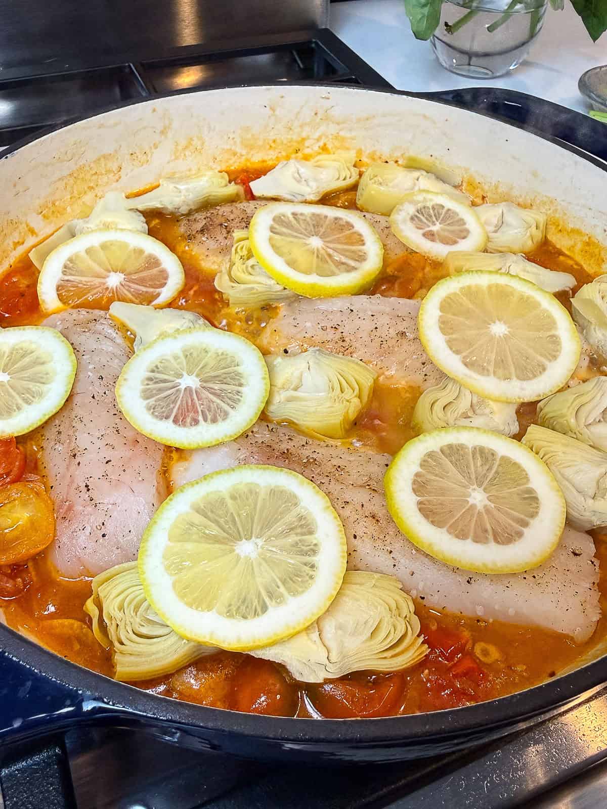 Layer lemon slices on top of the cod filets and let everything simmer until the fish is just cooked through.