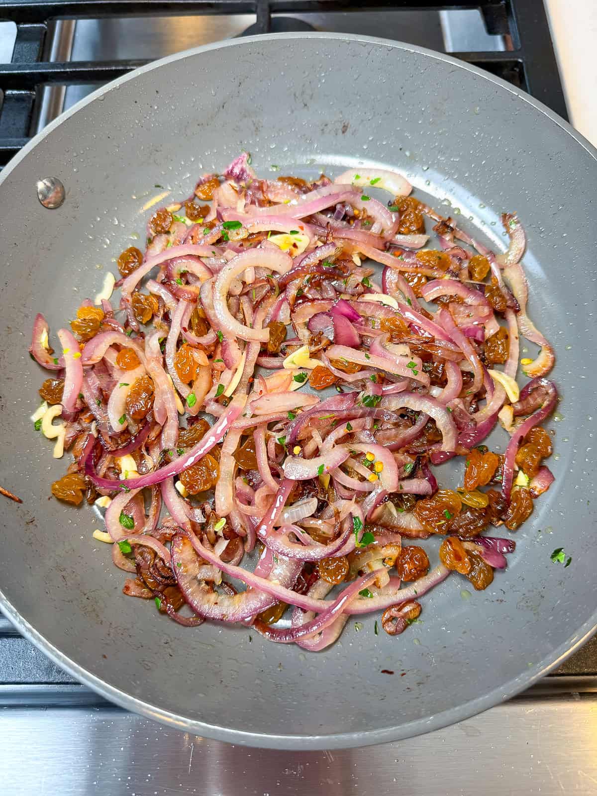 Add golden raisins to the sautéed onions.