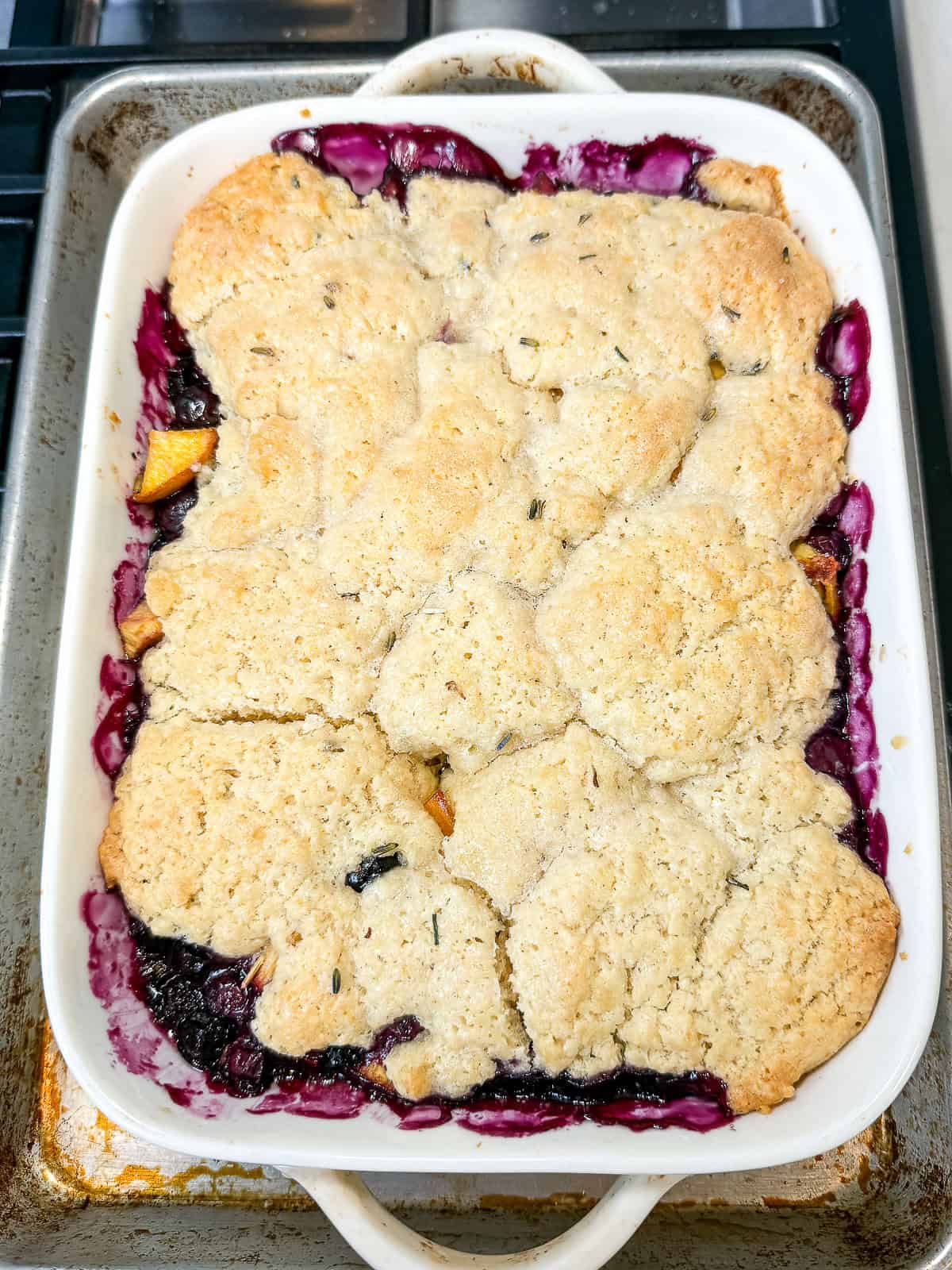 Bake the peach and blueberry cobbler until the fruit is tender and biscuit topping is lightly golden.