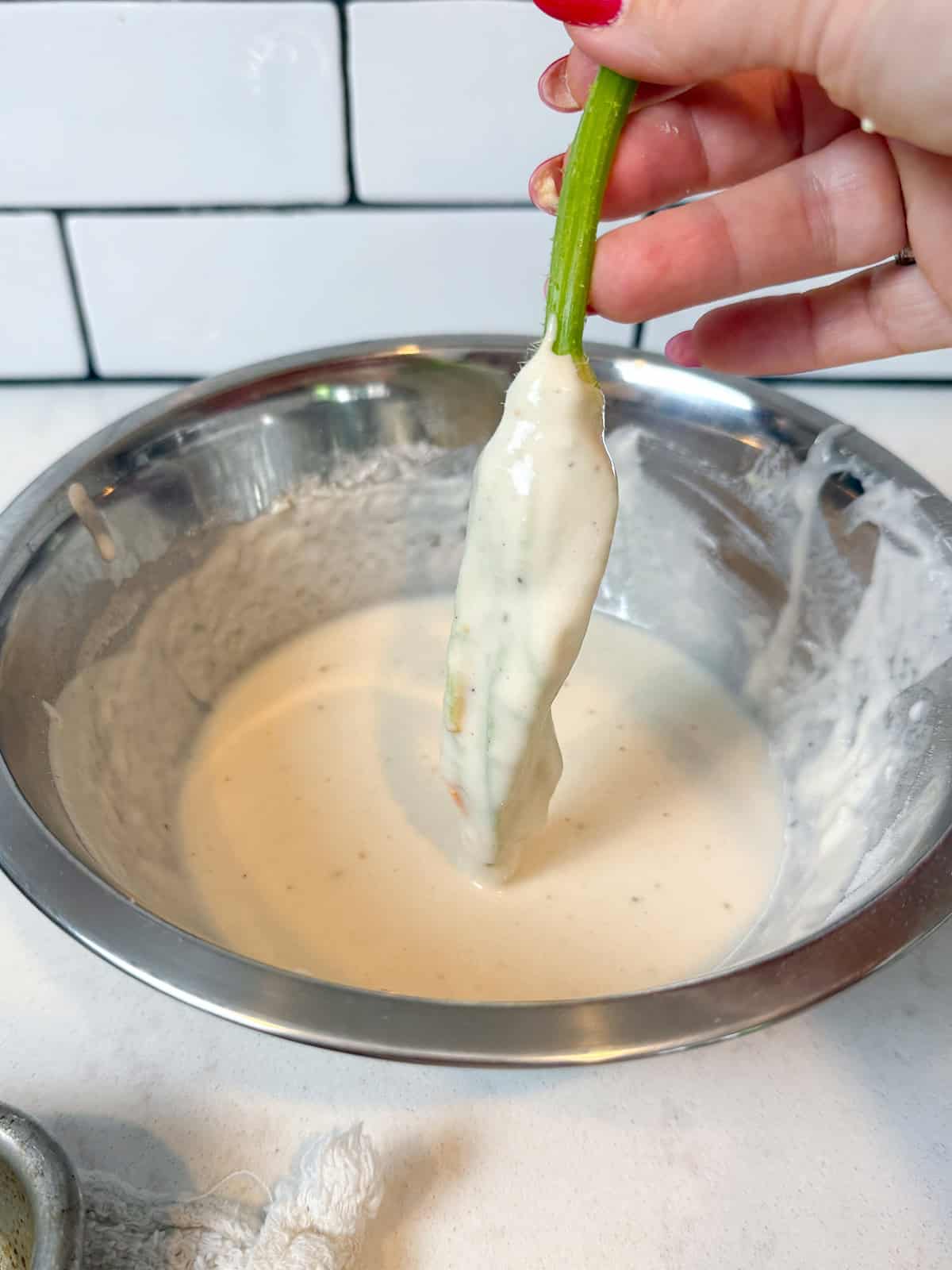 Dip the stuffed squash blossoms in the beer batter before frying.