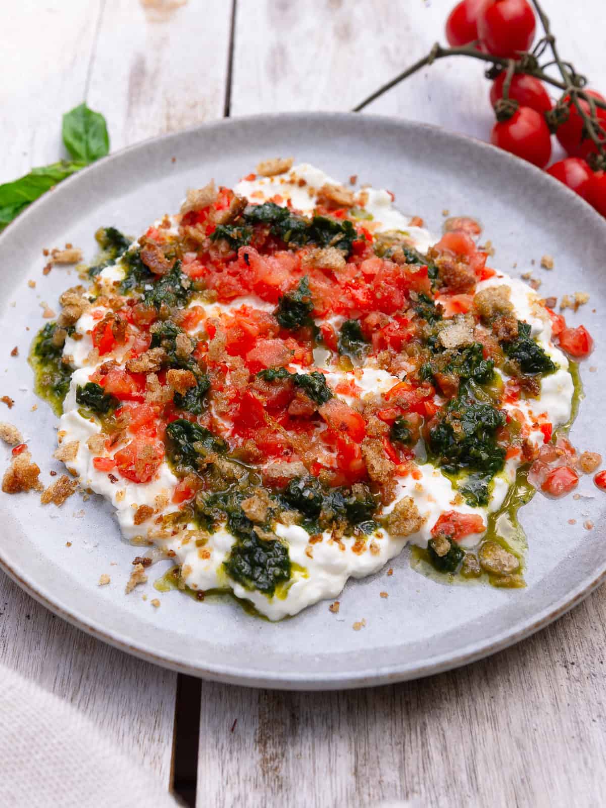 Frozen cherry tomatoes are grated and spooned over creamy stracciatella and garnished with basil oil and crispy breadcrumbs.