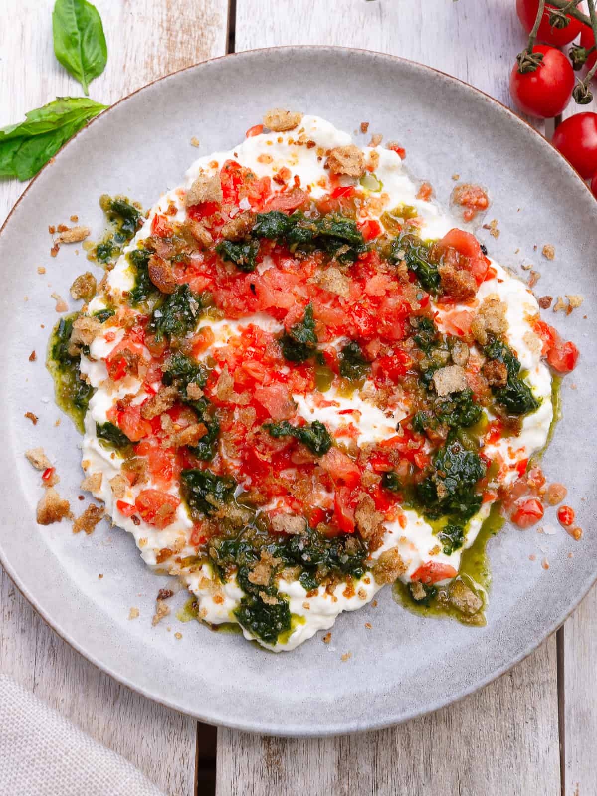 Frozen cherry tomatoes are grated and spooned over creamy stracciatella and topped with basil oil and crispy breadcrumbs.
