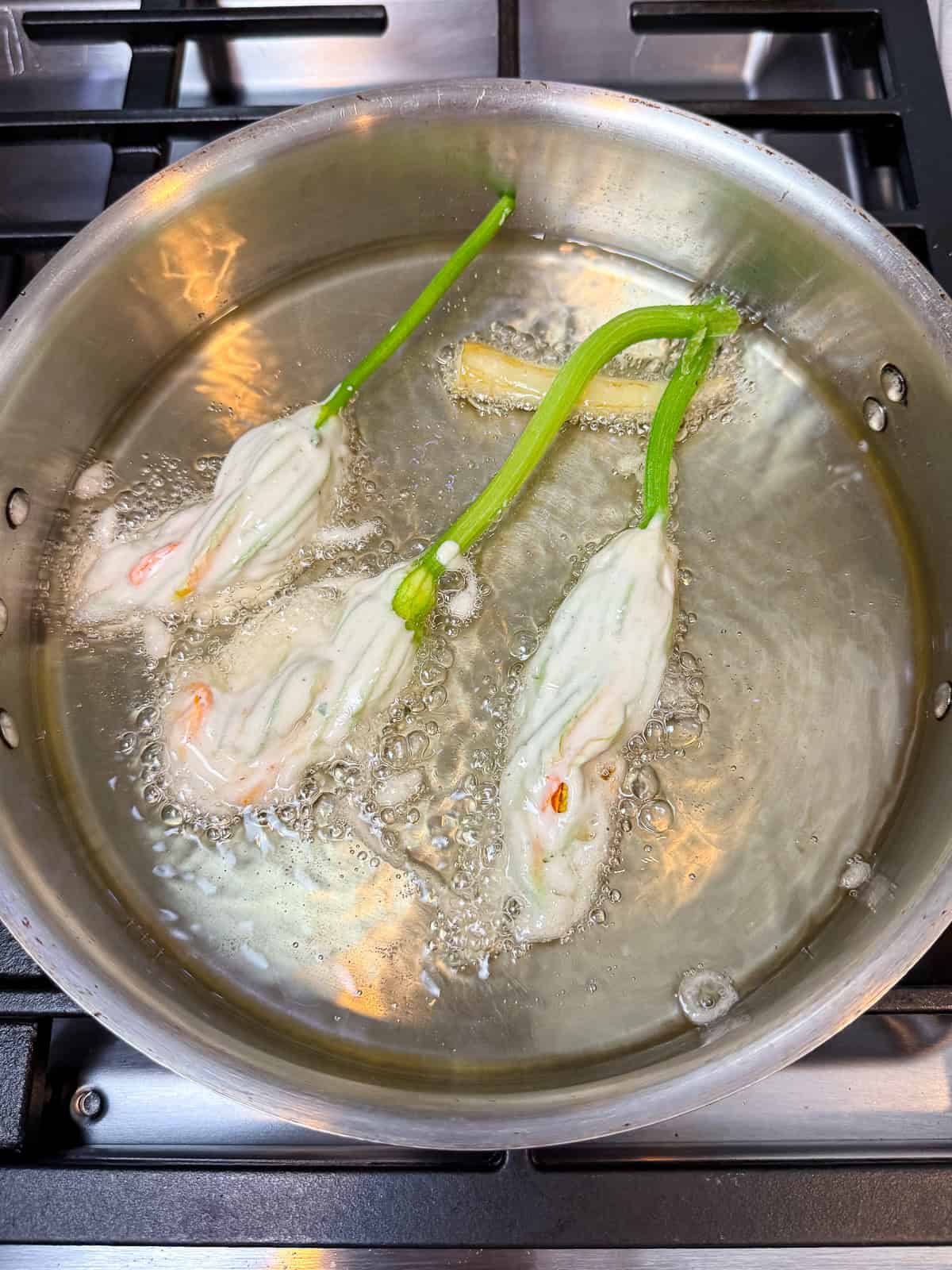 Add the beer batter dipped squash blossom in hot oil and fry until golden brown.