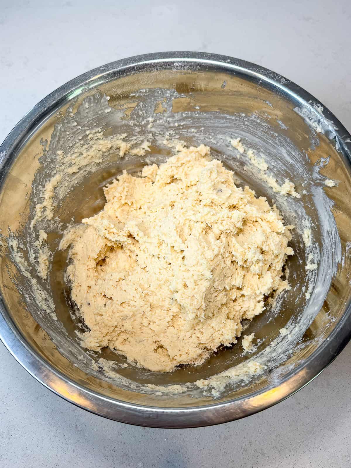 Add heavy cream to the flour and butter mixture to form the biscuit topping for the cobbler.