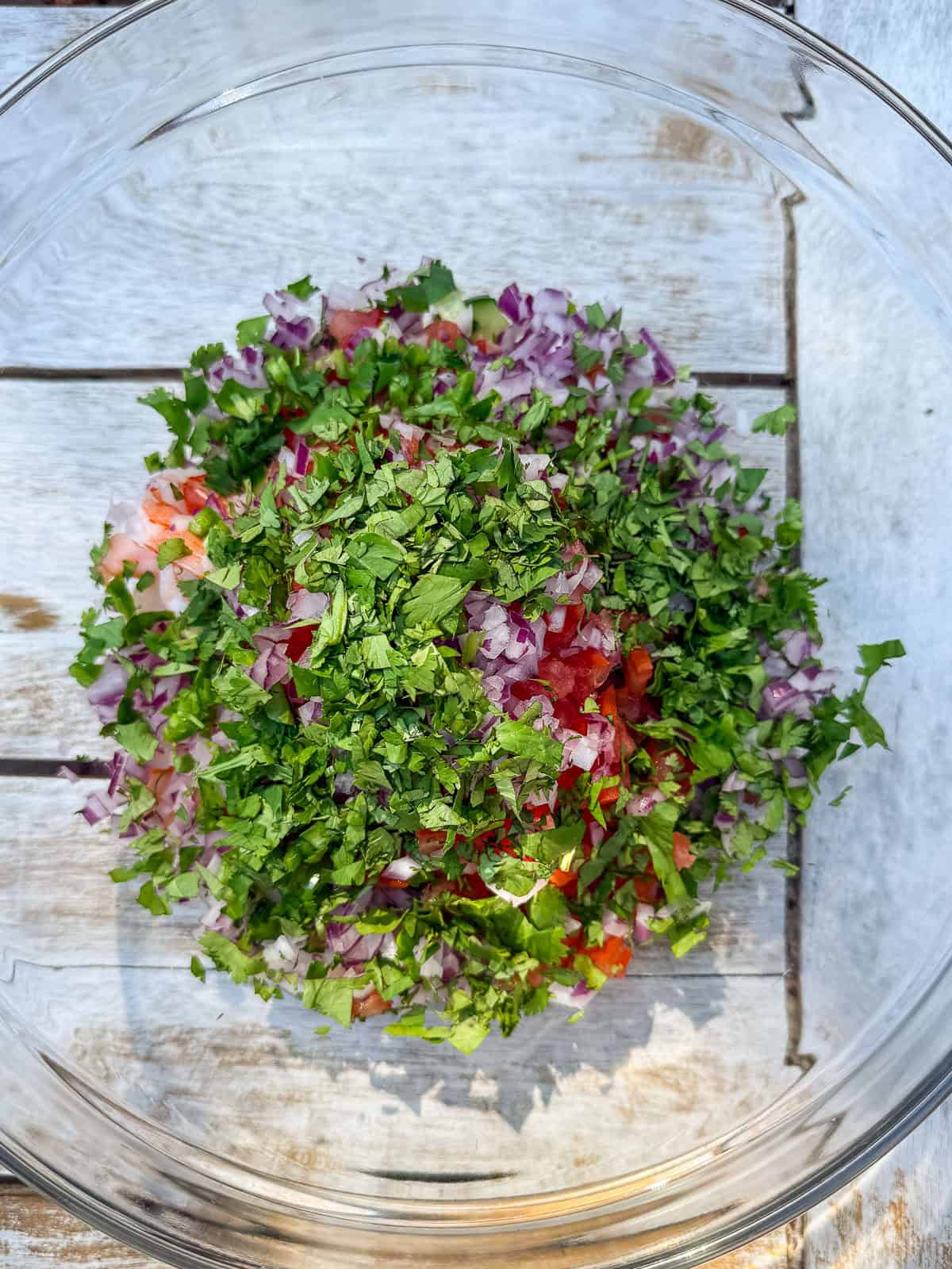 To a bowl, add the cooked shrimp, diced vegetables and fresh herbs.