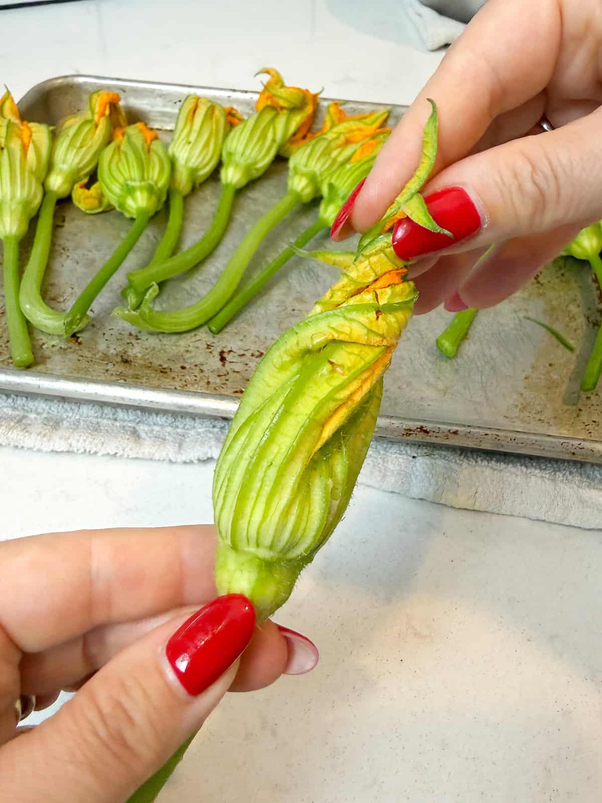 Once the squash blossom is filled with cheese, gently twist the flower closed before frying.