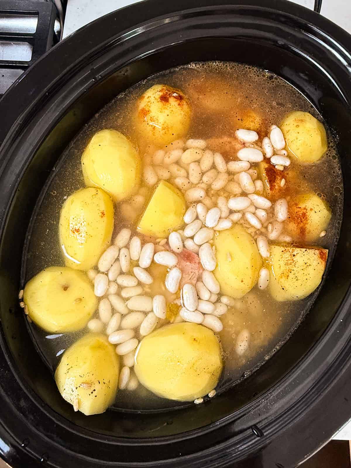 Add the potatoes, beans, barley and stock to the slow cooker cholent.