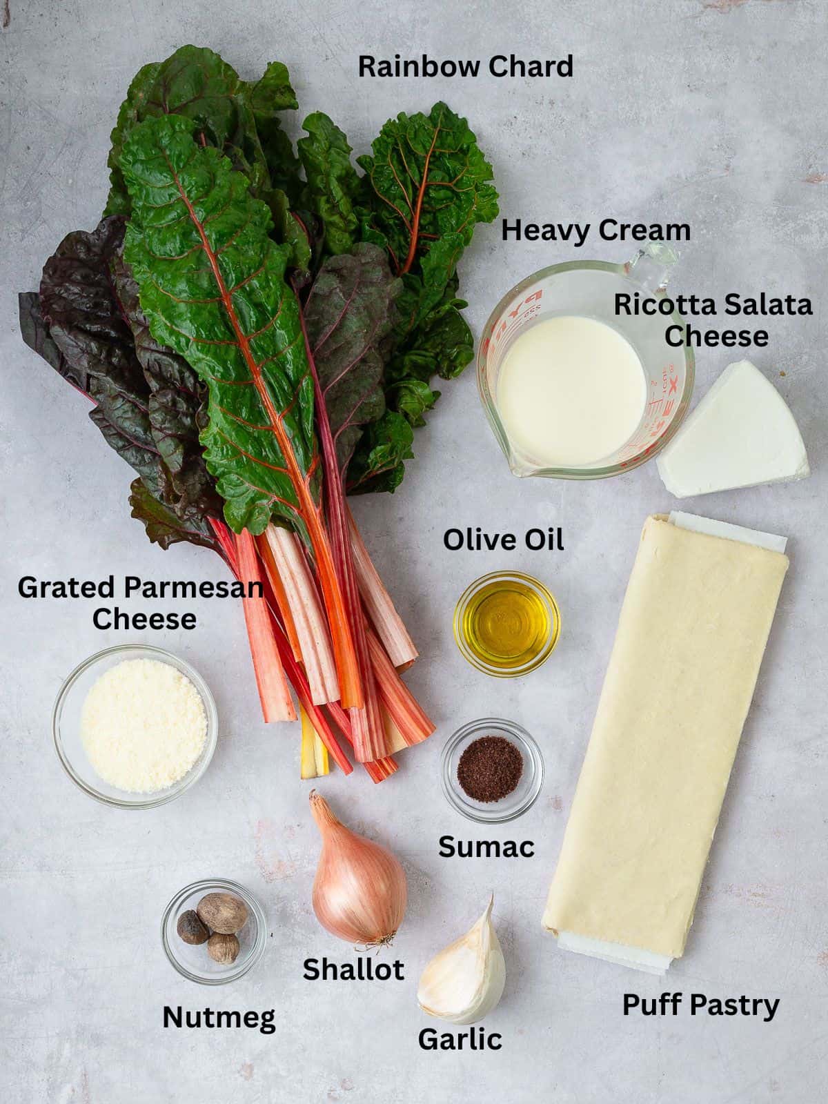 Ingredients for savory chard tart with grated parmesan cheese heavy cream, puff pastry and aromatics.