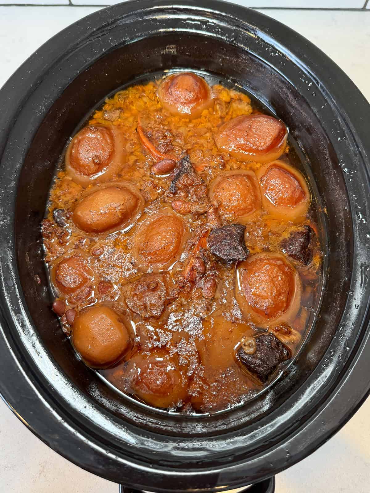 Cook the cholent in the slow cooker until the beef and vegetables are tender and stew has thickened.