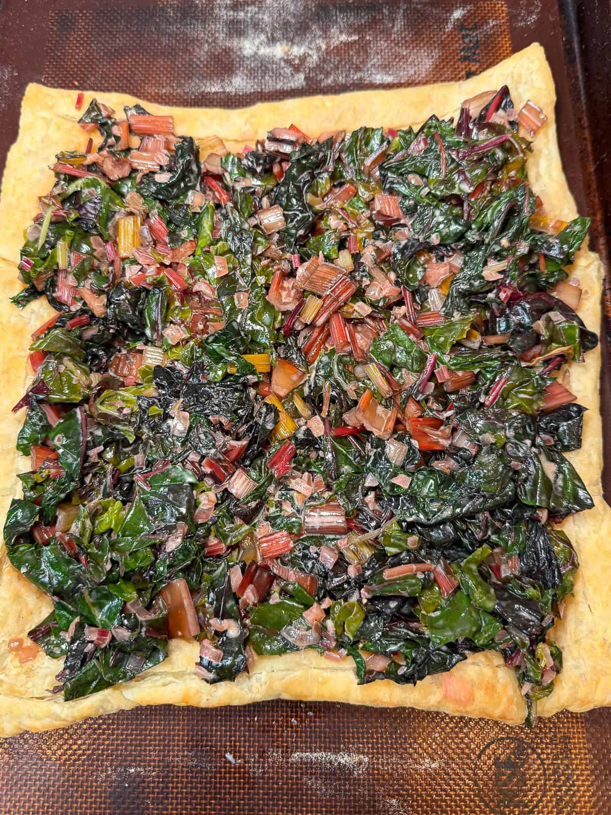 Layer the creamed chard onto the par-baked puff pastry, leaving a border of pastry and continue baking until tart is set.