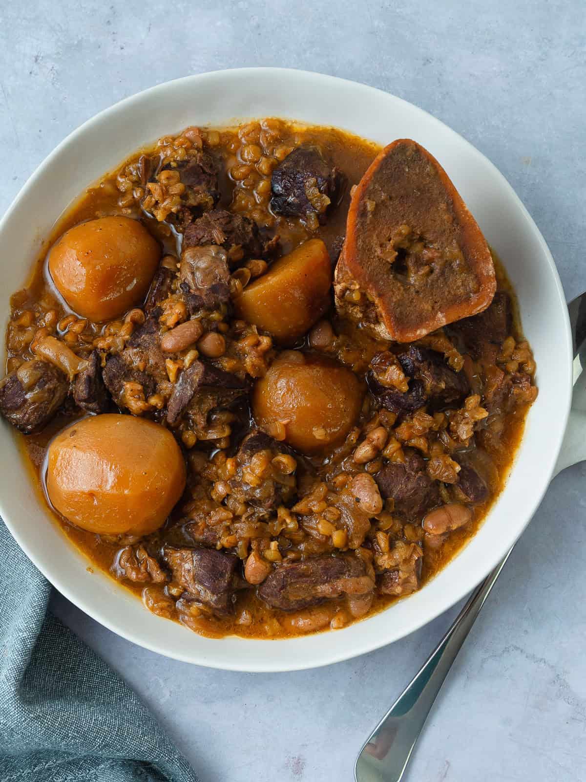 Homemade cholent served in a bowl with tender beef, potatoes, beans, and barley.