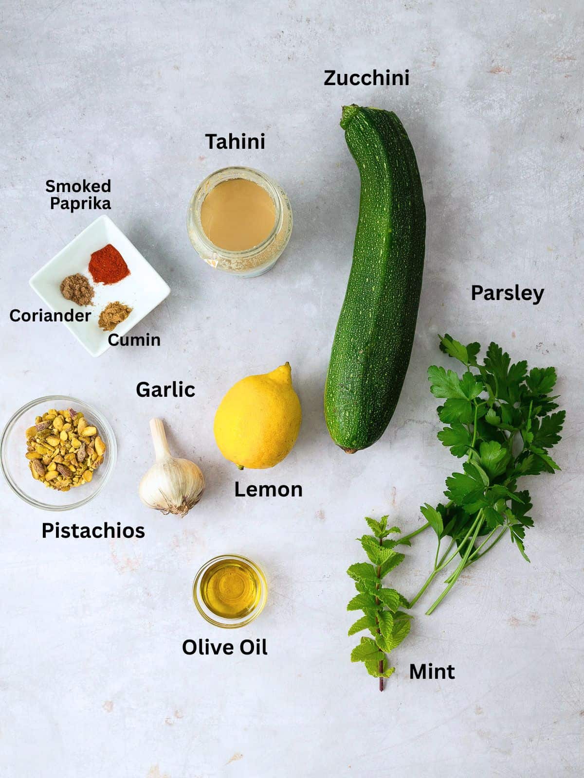 Ingredients for zucchini baba ghanoush, including spices, garlic, lemon, tahini and pistachios.
