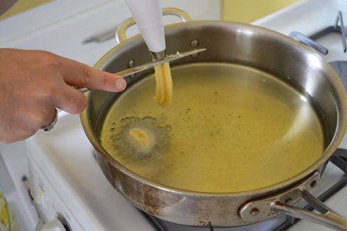 As you're piping the donuts into the oil, use a knife to cut the dough so the donuts are 2-3 inches long.