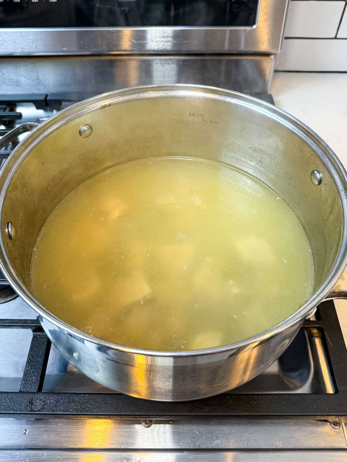 Remove the onion and garlic from the pork stock once it's finished cooking.