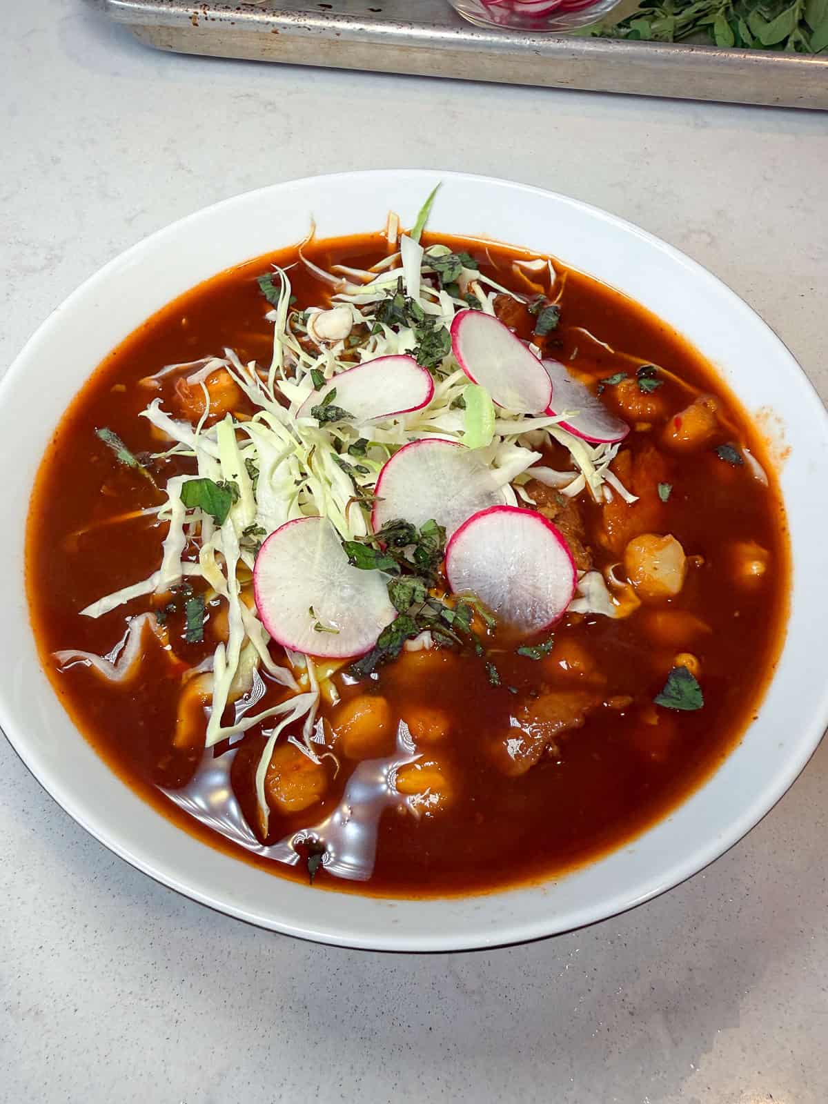 Garnish pozole rojo with shredded cabbage, sliced radish and oregano.