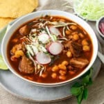 This pozole rojo is full of deep flavor with pork, chiles and garnished with shredded cabbage and sliced radish.